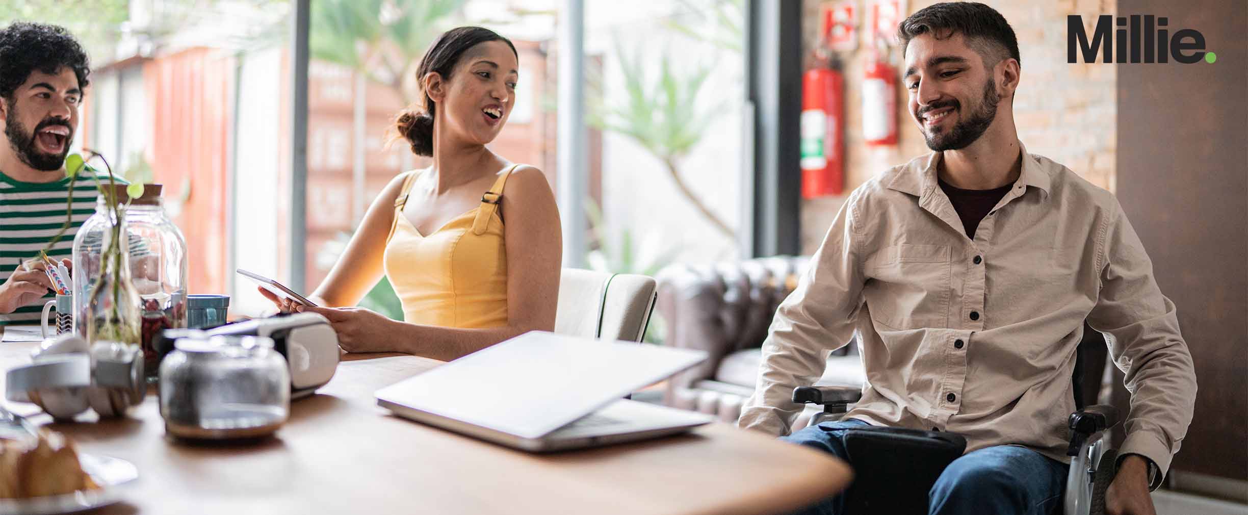 Two coworkers happily chatting with their boss who uses a wheelchair.