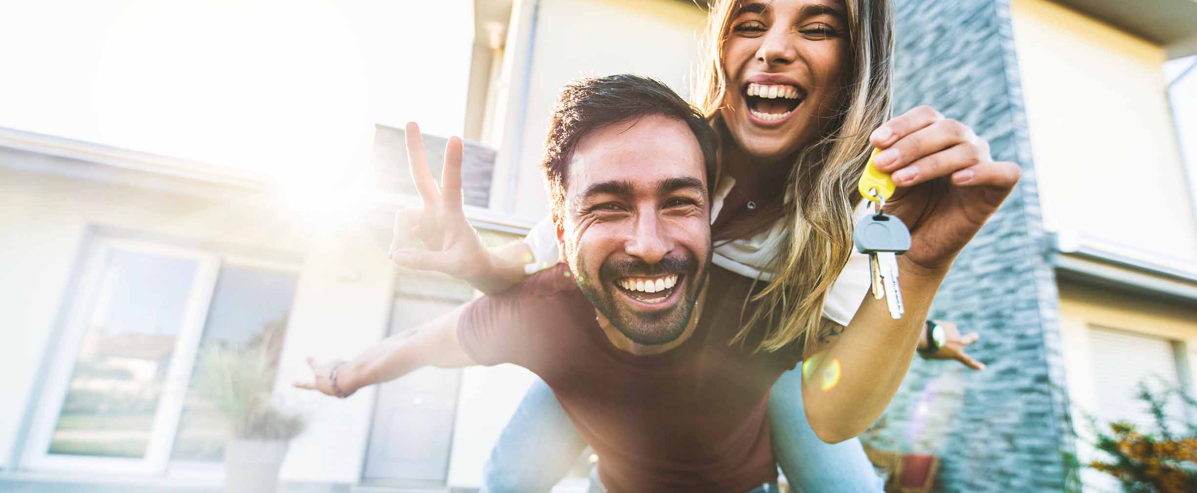 A young couple laughs and holds the keys to their new home