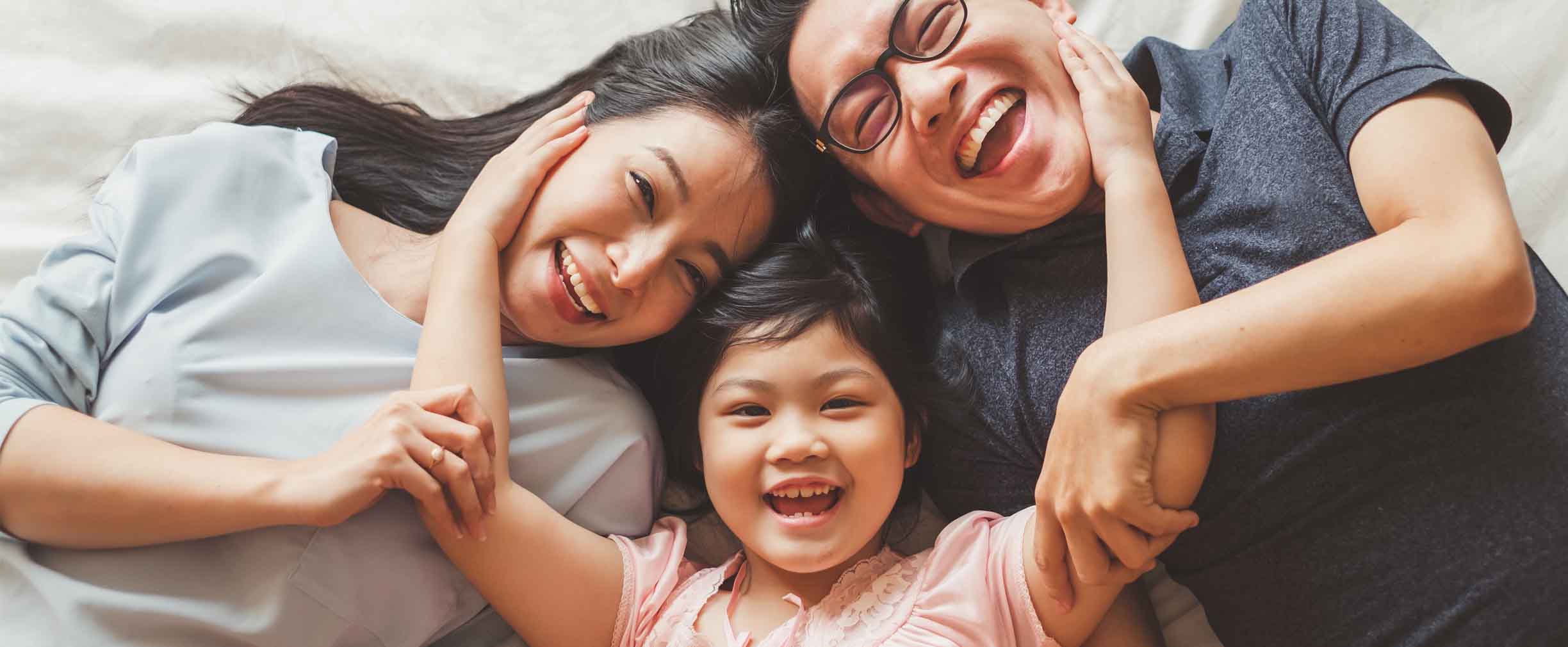 happy family lying on bed laughing and hugging