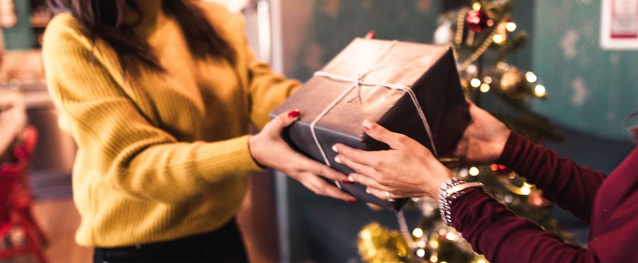 young woman reaching out to receive a Christmas gift from a friend