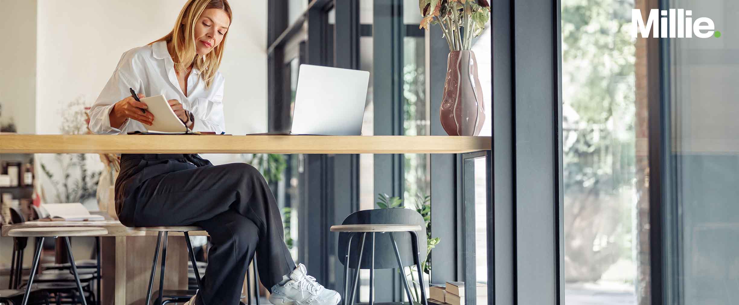 A female gig worker sitting at a desk with her laptop and a notepad.