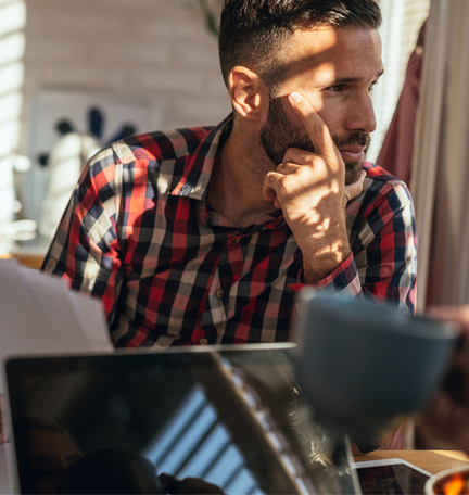 Stressed man sitting in the kitchen and holding papers